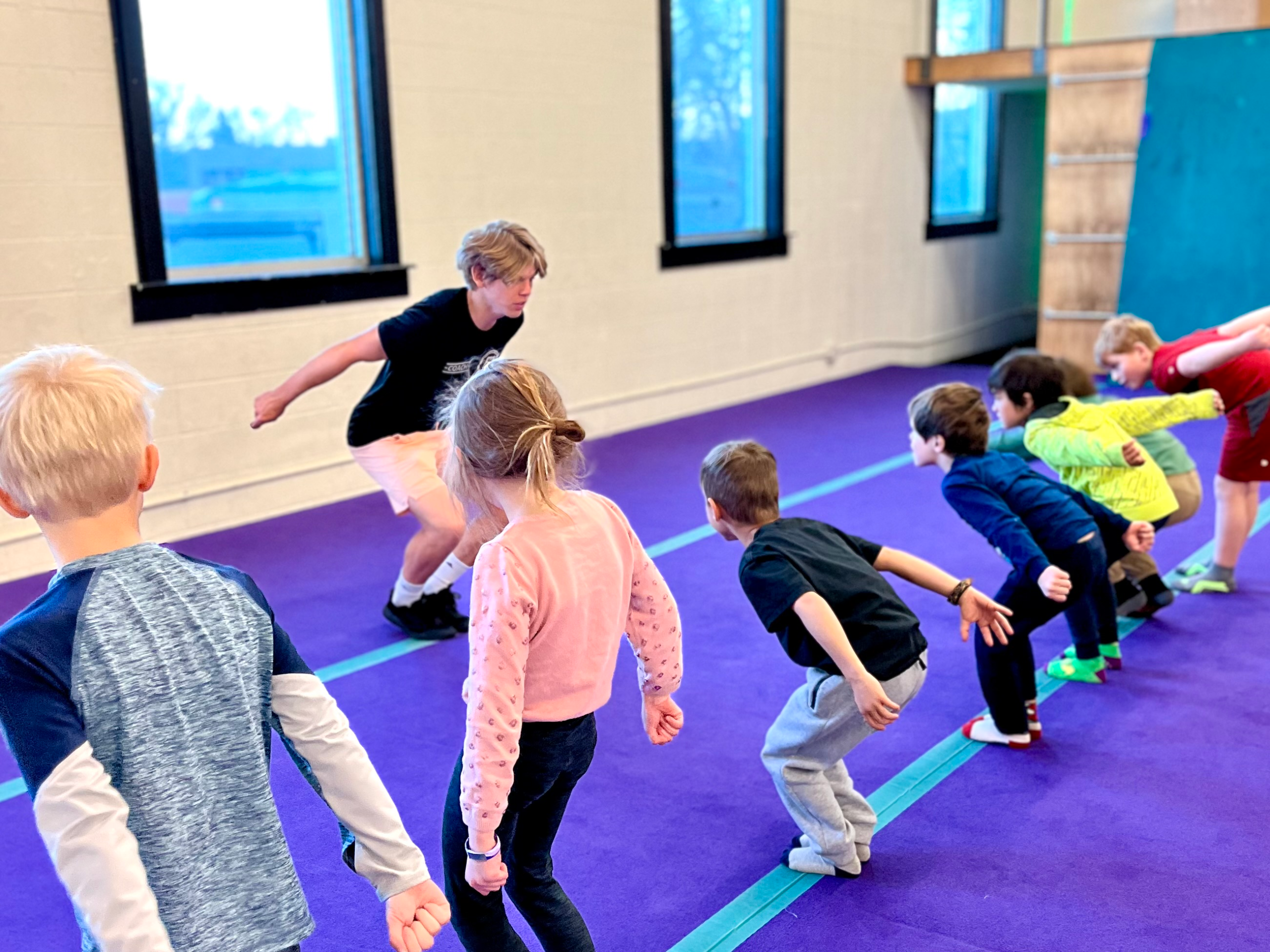 Student jumping from mini trampoline onto spring floor with coach supervision